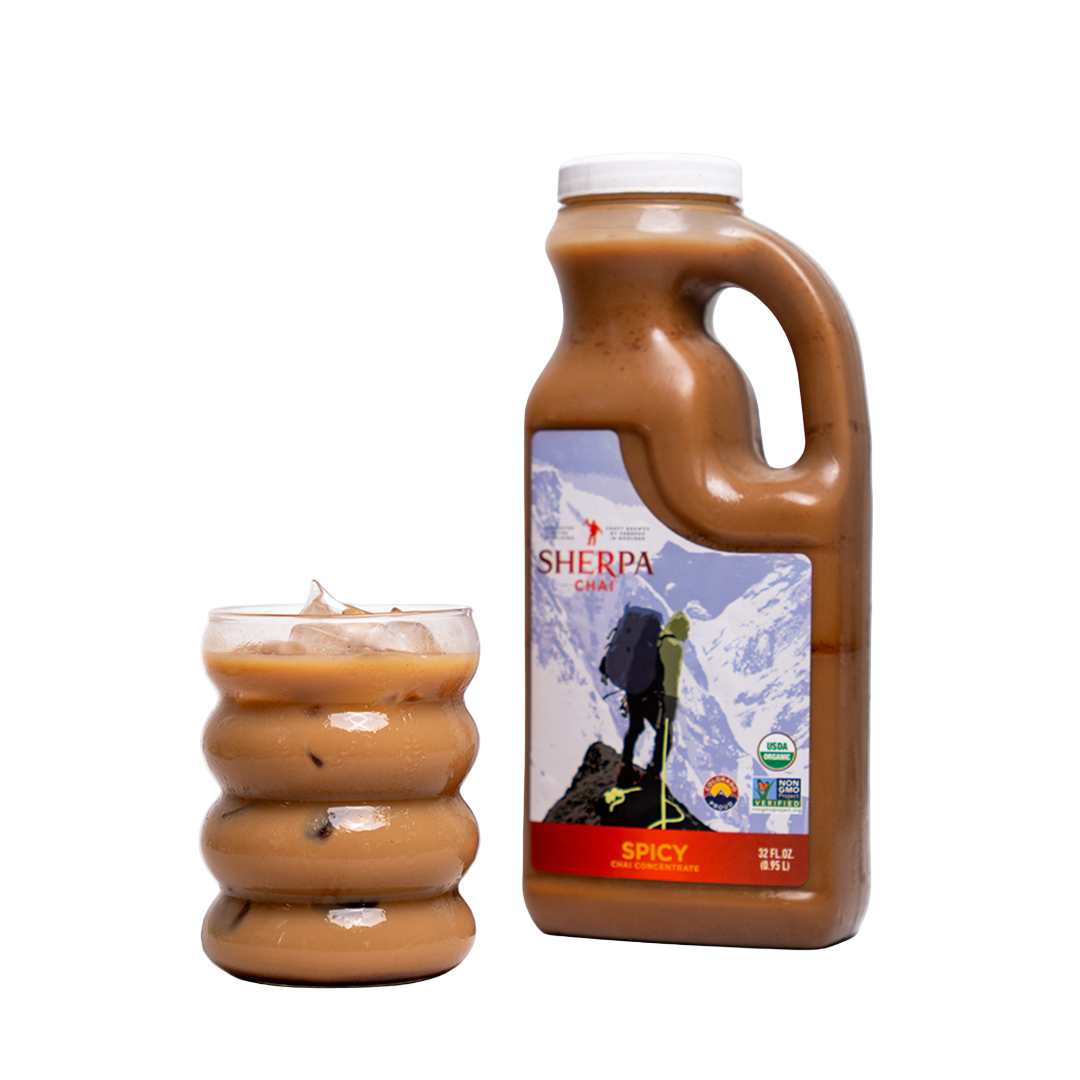 Bottle of Sherpa Spicy chili sauce with a glass of chili on a white background