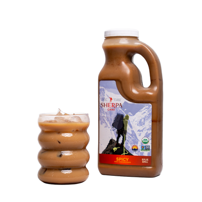 Bottle of Sherpa Spicy chili sauce with a glass of chili on a white background